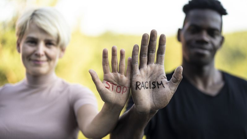 White woman and Black man with "Stop Racism" written on their hands.