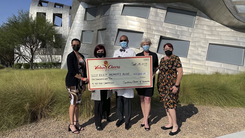 Group of people holding large donation check.